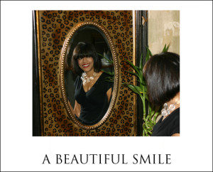 Dental Implant Cost web page: Woman with beautiful implant supported teeth smiles at herself in mirror