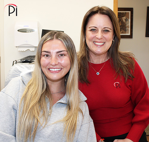 A patient treated with dental implants to restore congenitally missing teeth poses with her aunt.